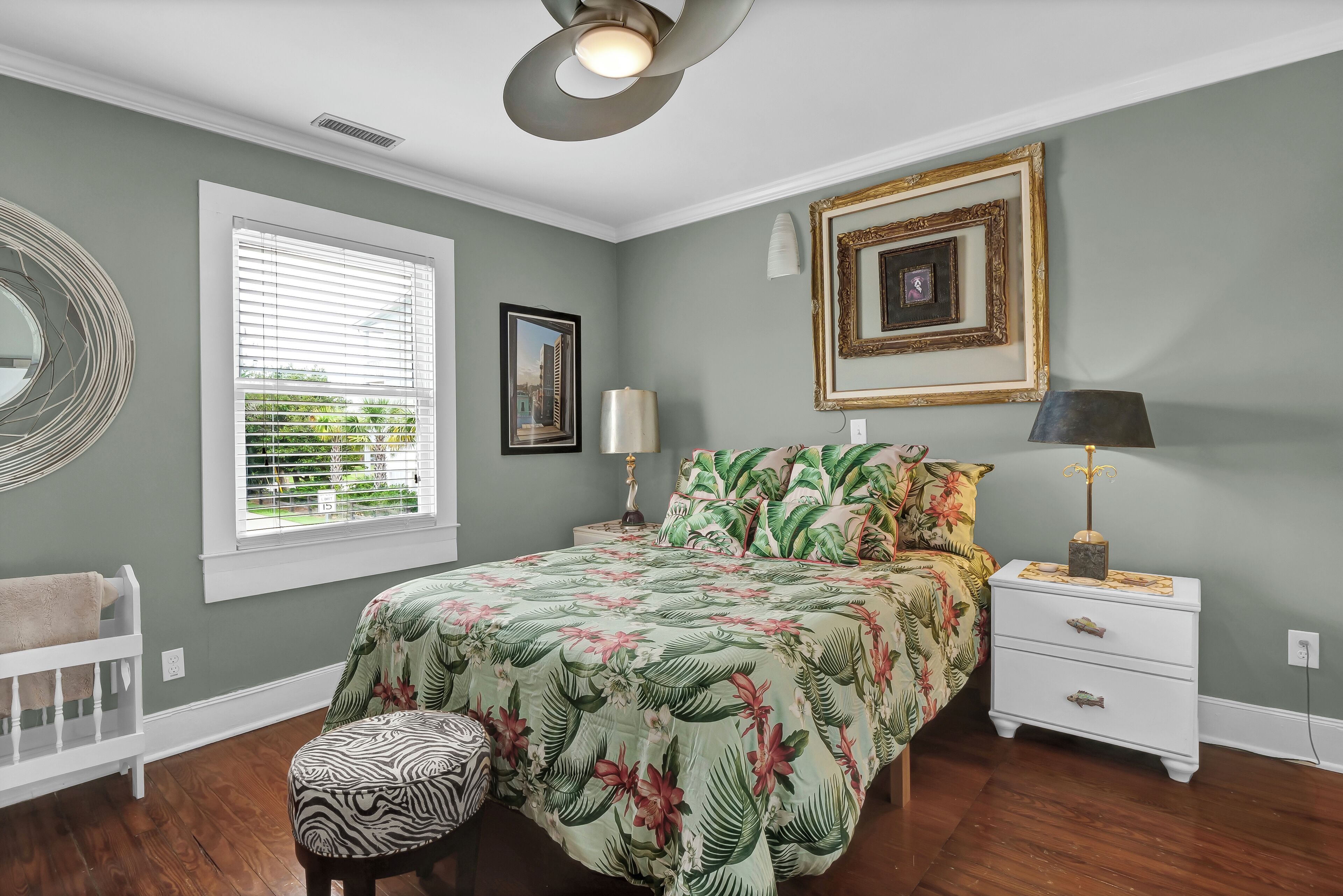 A bedroom with a bed, a nightstand, a lamp, a chair, and a window with blinds.