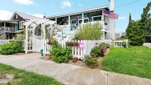 Ein zweistöckiges Haus mit Veranda, weißem Zaun und kleinem Garten.