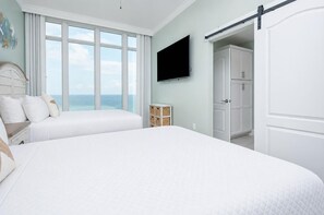 Un dormitorio con una cama grande, televisión, armario y vistas al océano.