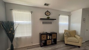 Una sala de estar con un sofá color beige, una estantería, un reloj y un letrero con la palabra 'HOME'.