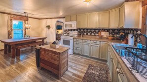 Una cocina amplia con suelo de madera, una zona de comedor con banco y una pequeña isla.