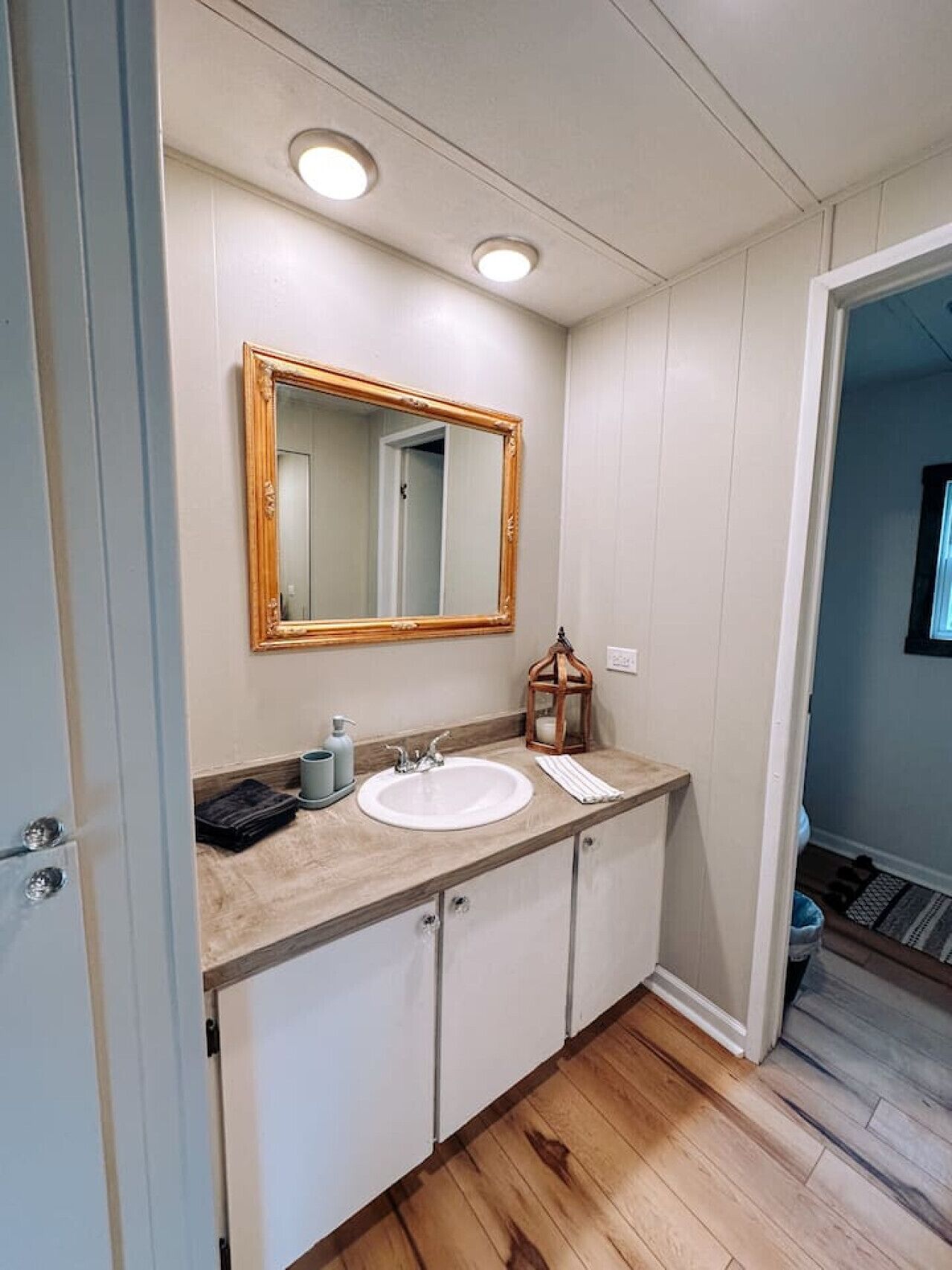 A bathroom with a wooden vanity, a large mirror, and a sink.