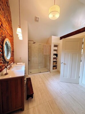 Bathroom features a large mirror, sink, and glass-enclosed shower area.