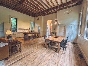 Relax in this open-plan living area with a high ceiling, featuring a dining space, kitchen, and comfortable seating.
