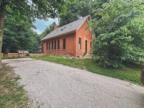Situated in a serene natural setting, this traditional building offers a peaceful retreat with a central entrance and lush surroundings.
