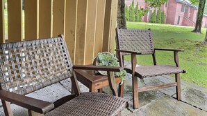 Two wicker chairs with a woven backrest and seat, placed on a concrete patio with a wooden fence in the background. - BeaverBox AC, Pool, Hot Tub, Sauna, Near Resort (Killington)