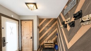A hotel entrance with a wooden door, a wall-mounted sign, and a shoe rack. - BeaverBox AC, Pool, Hot Tub, Sauna, Near Resort (Killington)
