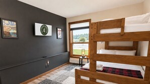A room with a bunk bed, a window with a view, a small table with a lamp, and wall decorations. - BeaverBox AC, Pool, Hot Tub, Sauna, Near Resort (Killington)