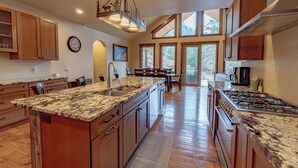 A spacious kitchen with granite countertops, wooden cabinets, and a large island. - Beautiful New Home with Views of Castle Mountain - 3510 (Estes Park)