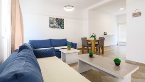 A modern living room with a blue sofa, a dining table with chairs, and a coffee machine.
