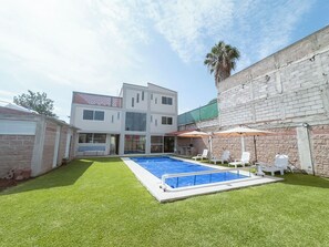 Enjoy a refreshing dip in the backyard pool surrounded by comfortable lounge chairs and shaded areas.