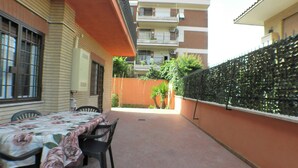 A patio area with a table and chairs, a brick floor, and a high fence. - B&B - Il Terrazzo da Gregorio - Room 2 (Roma)
