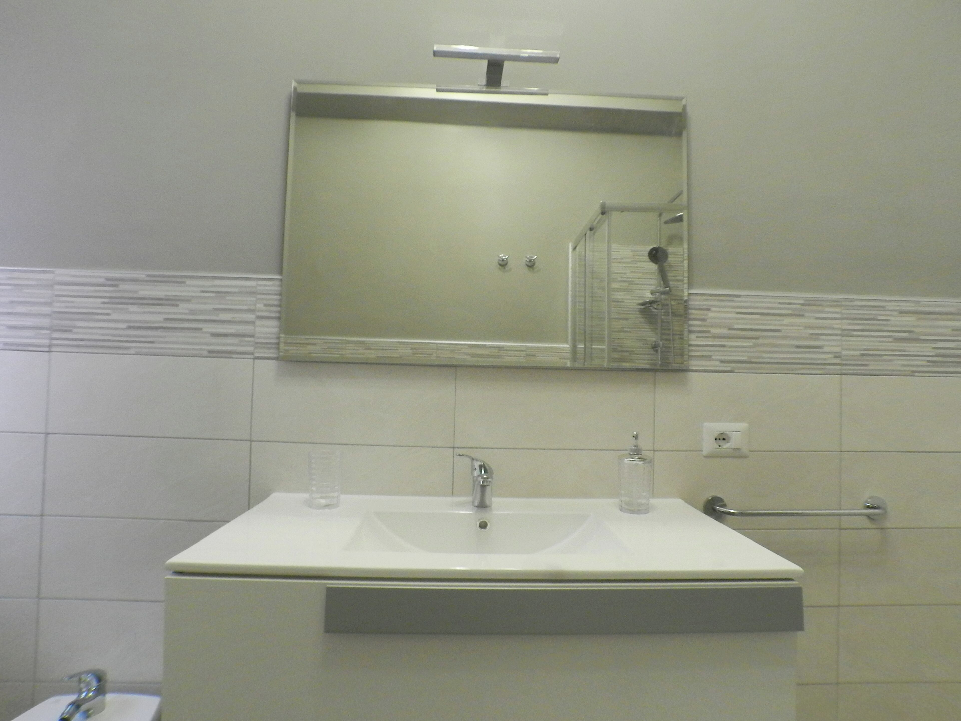 A bathroom with a white sink, mirror, and shower.
