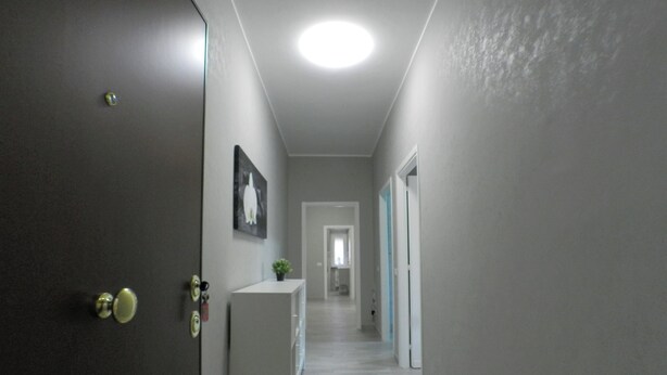 A hallway with a white console table, a door with a keyhole, and a ceiling light. - B&B - Il Terrazzo da Gregorio - Room 2 (Roma)