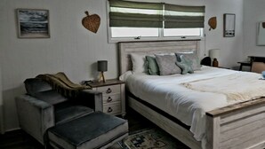 Ein Schlafzimmer mit Bett, Nachttisch, Stuhl und Teppich.