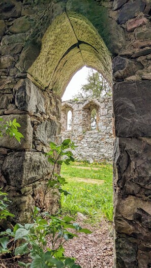 An ancient stone archway leading to a historic building with visible windows and stone walls.