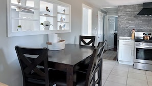 A modern kitchen with white cabinetry, a built-in oven, and a dining area with a dark wooden table and chairs.