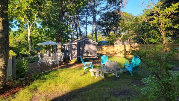 A backyard with a wooden shed, a small table, and several chairs.
