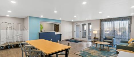 Una habitación de hotel moderna con zona de comedor, kitchenette y una sala de estar con sofá y sillón.
