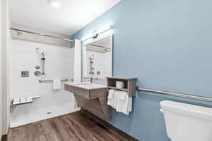 A modern bathroom with a walk-in shower, a vanity with a mirror, and a toilet. - WoodSpring Suites Centennial - Denver Tech Center (Centennial)