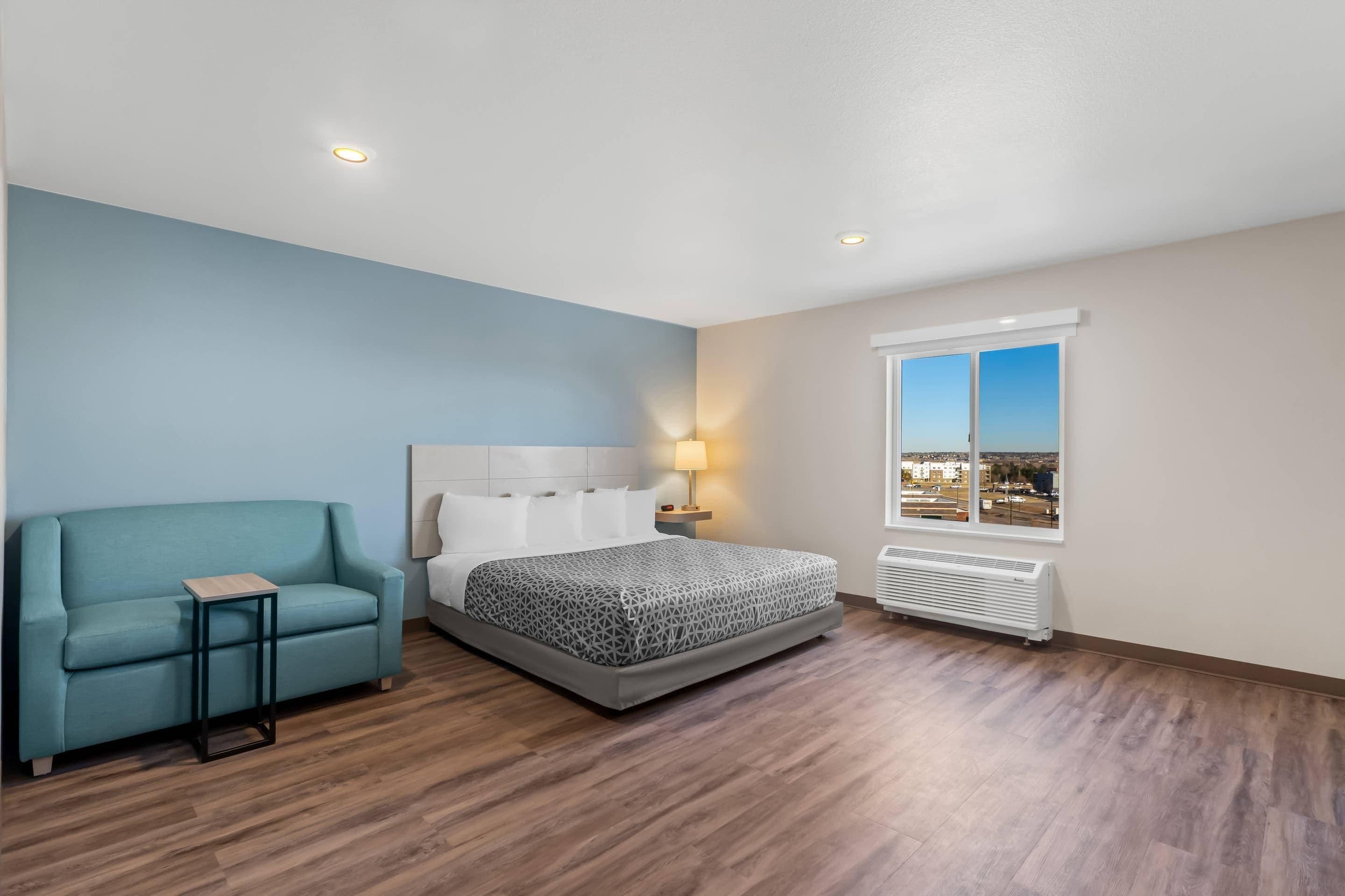 A bedroom with a bed, a chair, a nightstand, a window with a view, and a radiator.