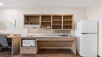 A compact kitchen with a built-in microwave, a sink, and a refrigerator.