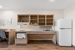 Una cocina compacta con microondas integrado, un lavamanos y un refrigerador.