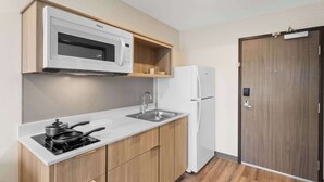 A compact kitchen with a microwave, stove, sink, and refrigerator. - WoodSpring Suites Centennial - Denver Tech Center (Centennial)