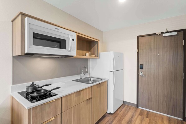 A compact kitchen with a microwave, stove, sink, and refrigerator. - WoodSpring Suites Centennial - Denver Tech Center (Centennial)