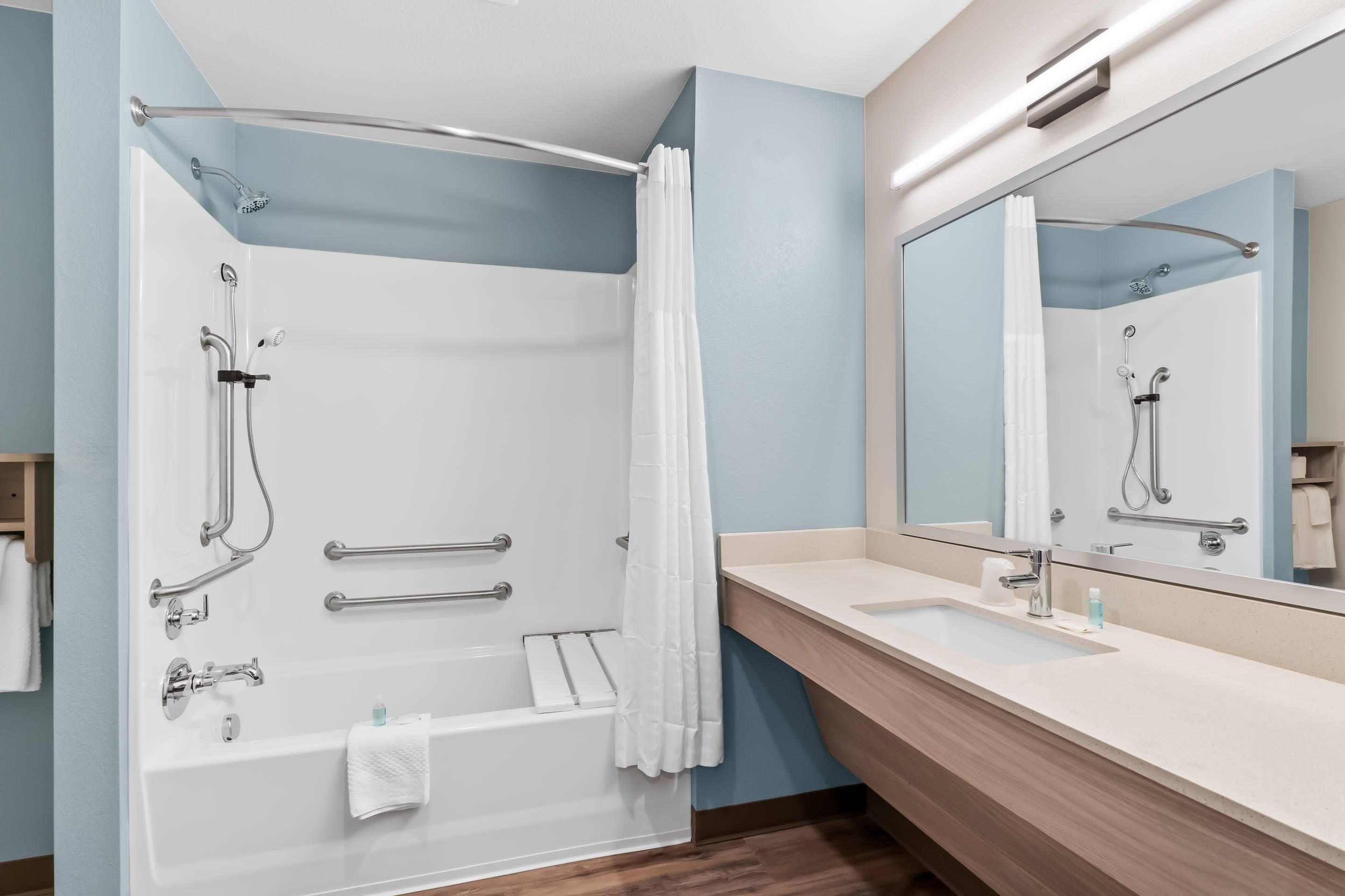 A modern bathroom with a bathtub, shower, and vanity.