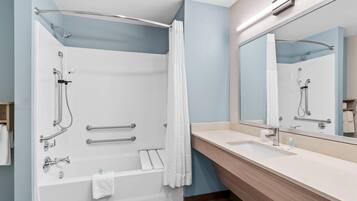 A modern bathroom with a bathtub, shower, and vanity.