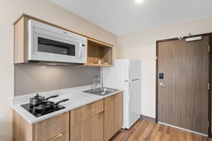 A compact kitchen with a microwave, stove, sink, and refrigerator. - WoodSpring Suites Centennial - Denver Tech Center (Centennial)