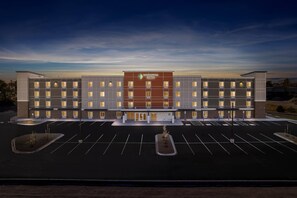 A hotel with a central entrance, multiple floors, and a parking lot.
