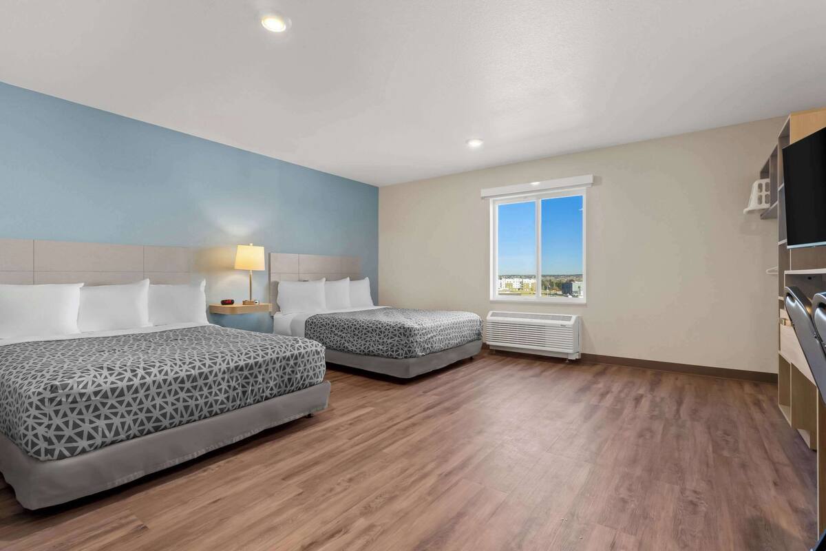 Habitación de hotel con dos camas, una ventana con vista a la ciudad, un televisor y un calentador.
