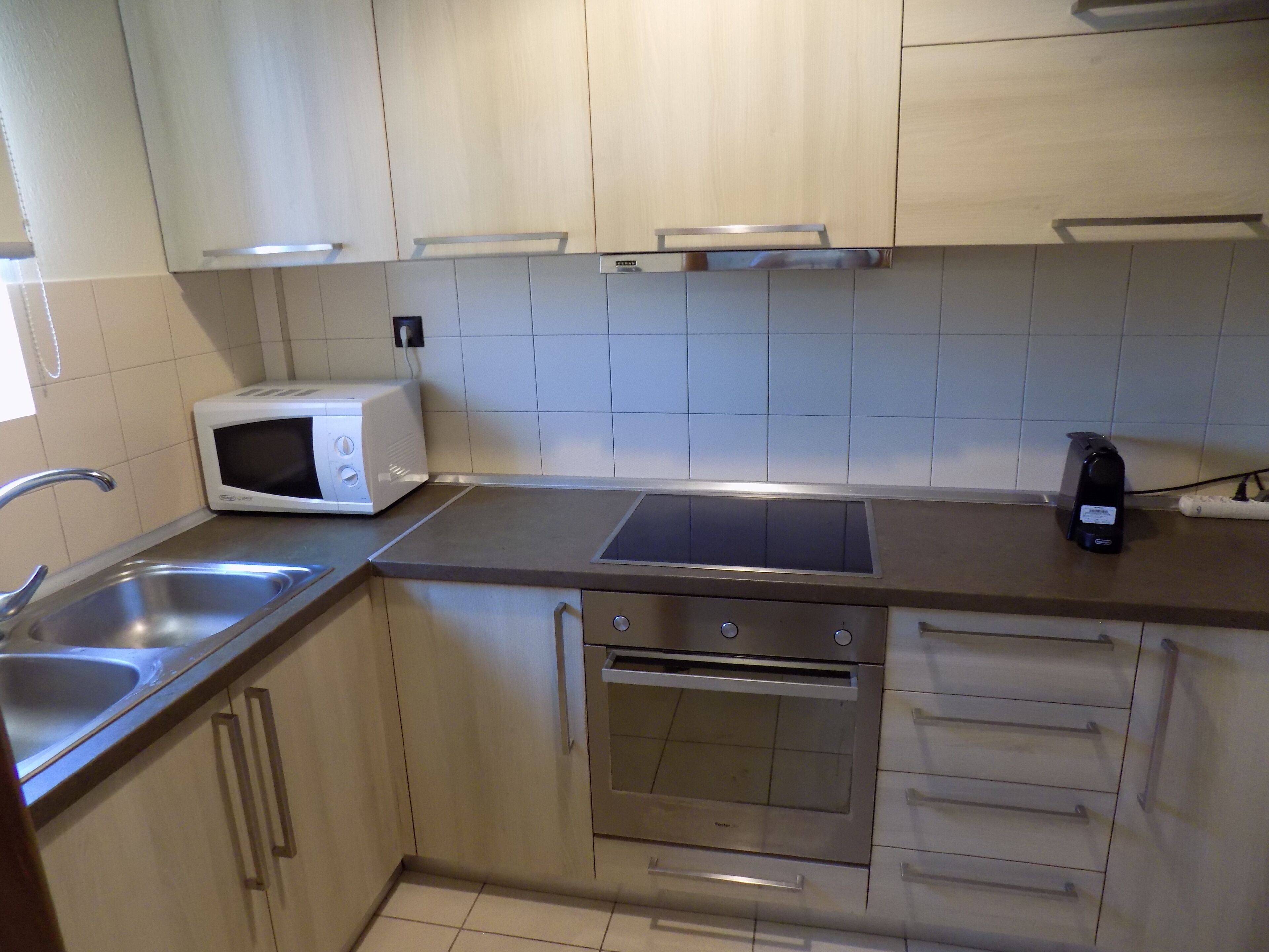 A modern kitchen with a microwave, oven, and stainless steel sink.