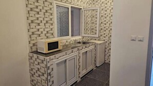 Una cocina estrecha con armarios blancos, un microondas en la encimera y una ventana sobre el fregadero.