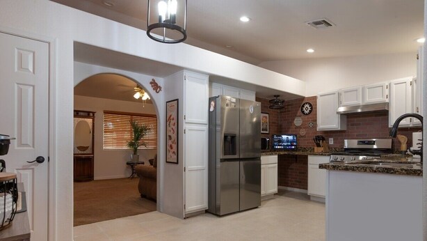 A modern kitchen with stainless steel appliances, white cabinetry, and a brick accent wall. - Spacious Route 66 retreat. Golf Course. Pet Friendly. Grand Canyon and Vegas. (Kingman)