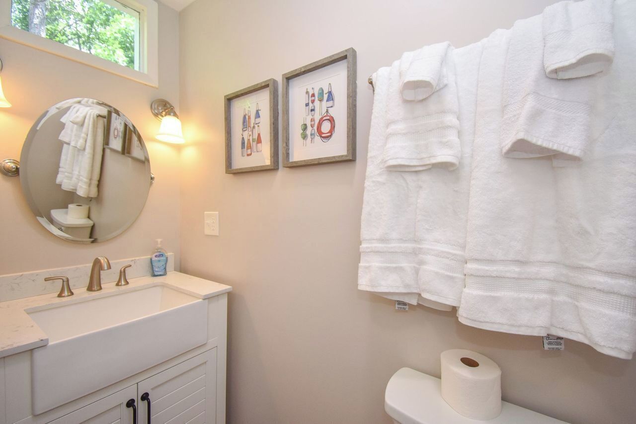 A bathroom with a white sink, a round mirror, and two framed pictures on the wall.