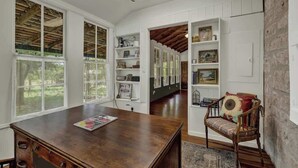Una habitación amplia con ventanas grandes, muebles de madera y estanterías empotradas.