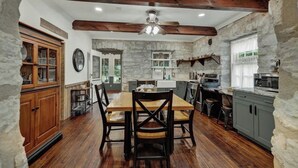 Una cocina rústica con vigas de madera, paredes de piedra y una mesa de comedor de madera con sillas.