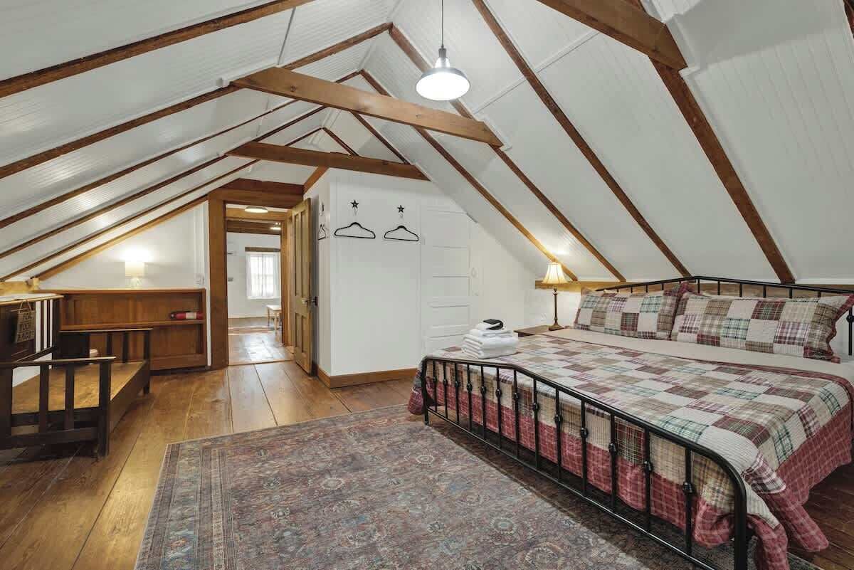 A cozy attic bedroom with a bed, a desk, and a wardrobe.