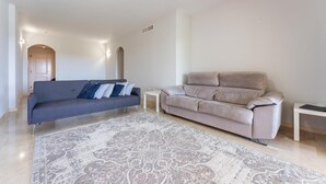 Een woonkamer met een grijze bank, een beige bank en een kamerbreed tapijt met een patroon.