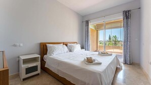 Een slaapkamer met een bed, nachtkastje en een raam met gordijnen.