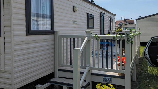 A mobile home with a porch, steps, and a welcome sign.