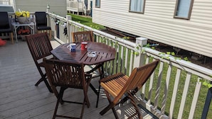 A deck with a round table and four chairs, surrounded by a white fence.