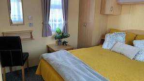 A hotel room with a bed, a desk, a chair, a wardrobe, and a window with curtains.