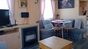 A cozy living area with a sofa, a small table, a television, and a fireplace.