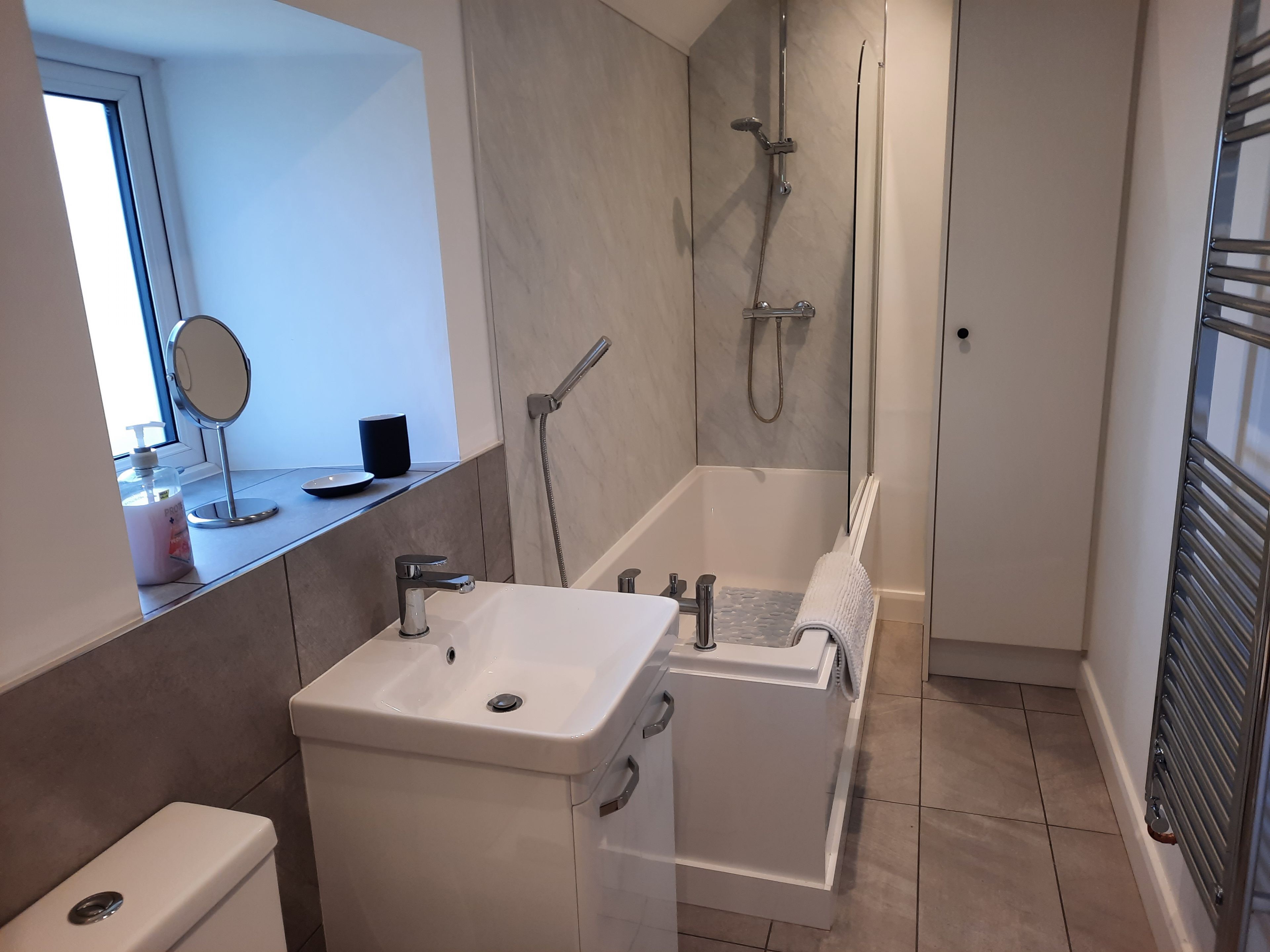 A modern bathroom with a sink, mirror, and shower.