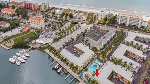 An aerial view of a coastal hotel area with a marina, swimming pool, and beachfront. - Water View Condo Across from Beach + Access to Amenities (Indian Shores)