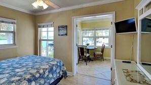 A bedroom with a bed, a ceiling fan, a dining area with a table and chairs, and a TV on a stand. - Water View Condo Across from Beach + Access to Amenities (Indian Shores)